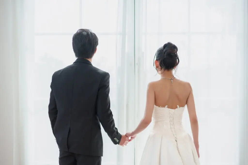 Bride and groom holding hands, back view.