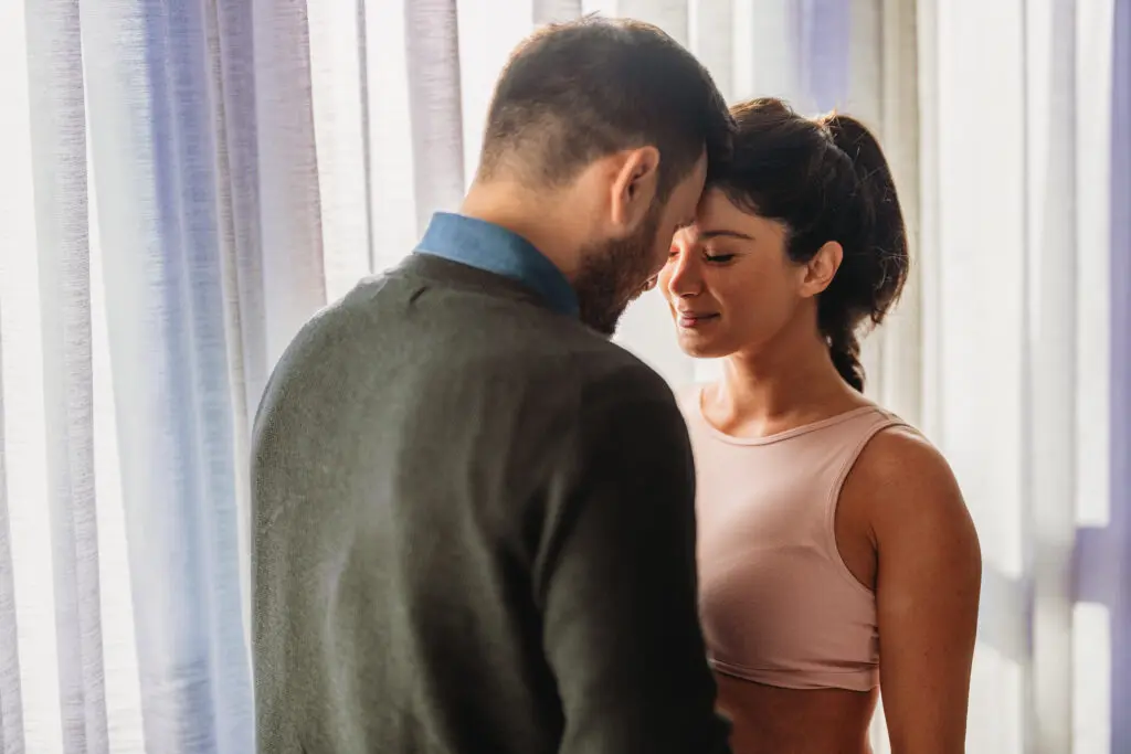 Man and woman standing close, gently smiling.